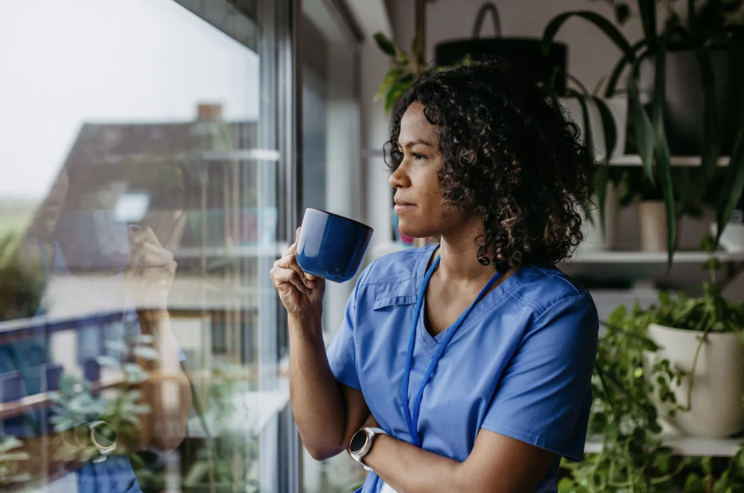 A woman drinking a coffee looking at a window