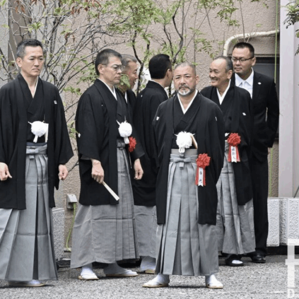 A few middle aged man wearing kimono standing up and talking