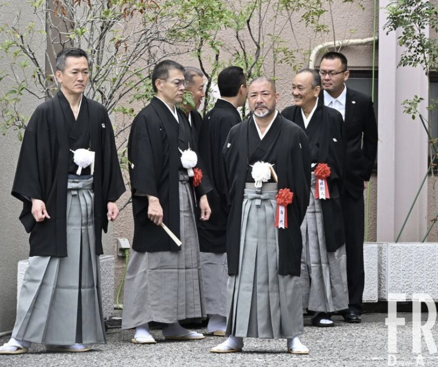 A few middle aged man wearing kimono standing up and talking 