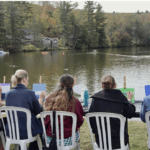 A group of woman sitting and painting at the lake