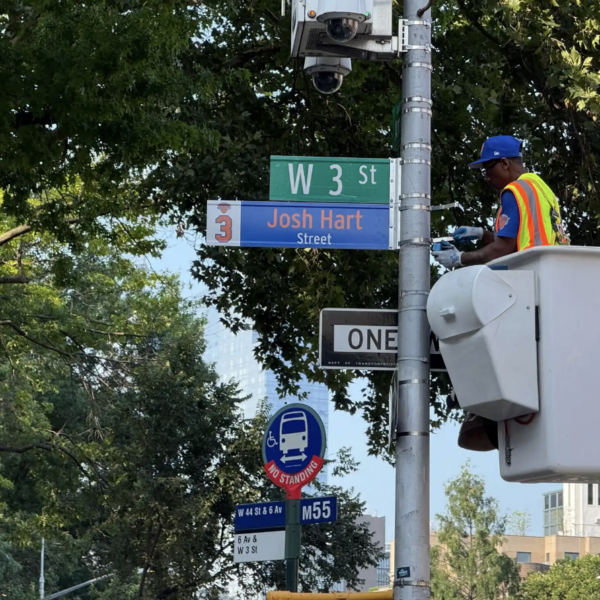 A NYC DOT worker installs a temporary street sign bearing Knicks championship team starter Josh Hart’s name and jersey number at the corner of Manhattan’s Sixth Avenue and 3rd Street.